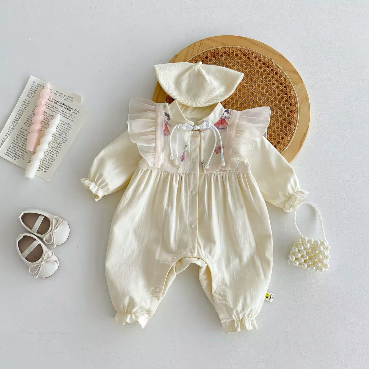 Cream princess style baby jumpsuit styled with matching hat and shoes