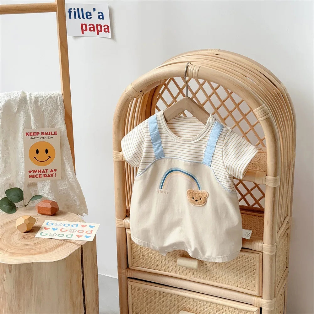 Rainbow bear striped baby romper on a rattan chair