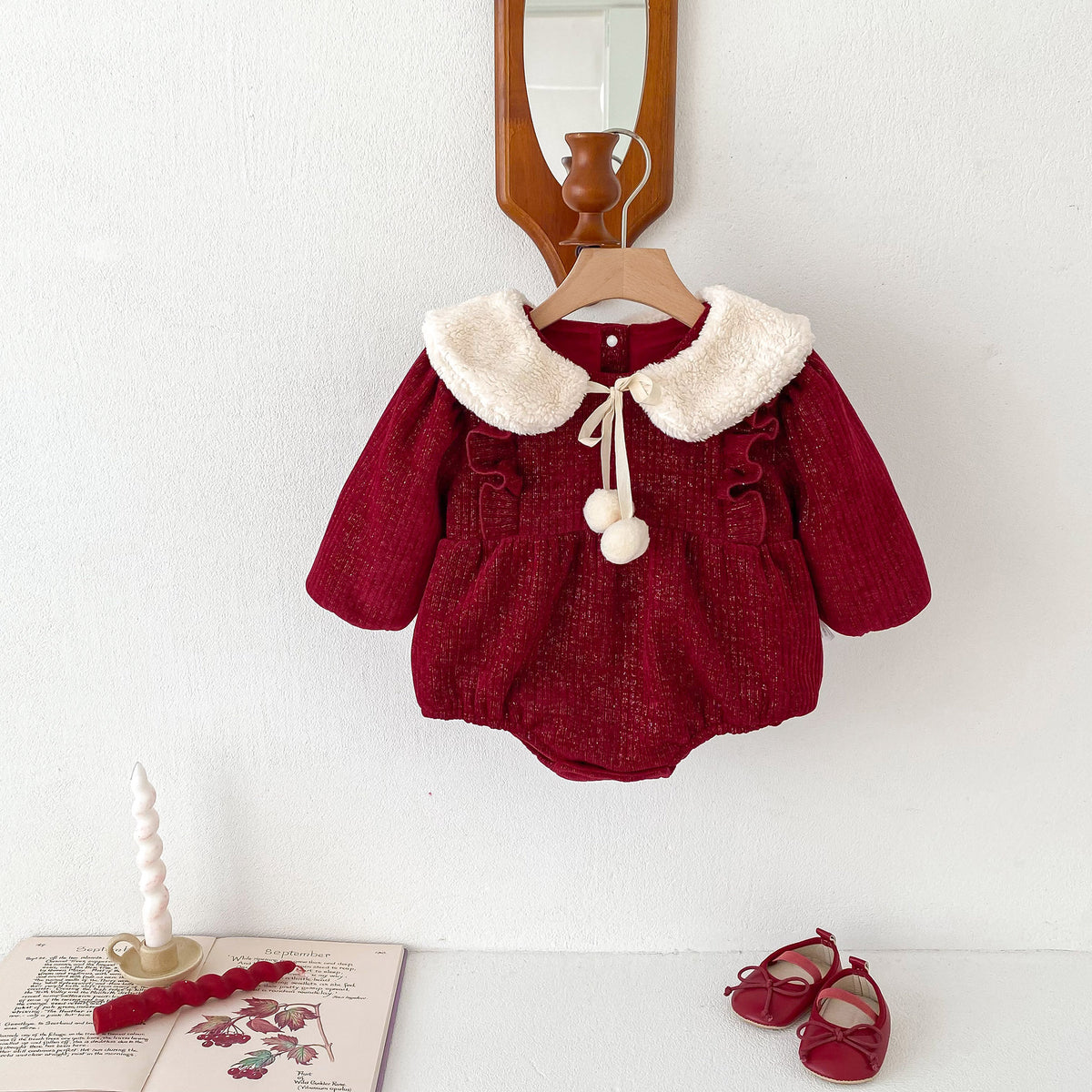Red baby romper with cream Peter Pan collar on a hanger