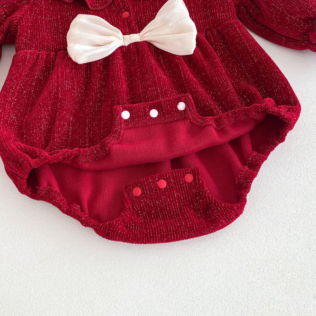 Close-up of snaps and bow on red baby romper