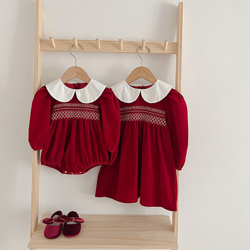 Red smocked romper and dress with Peter Pan collars on hangers