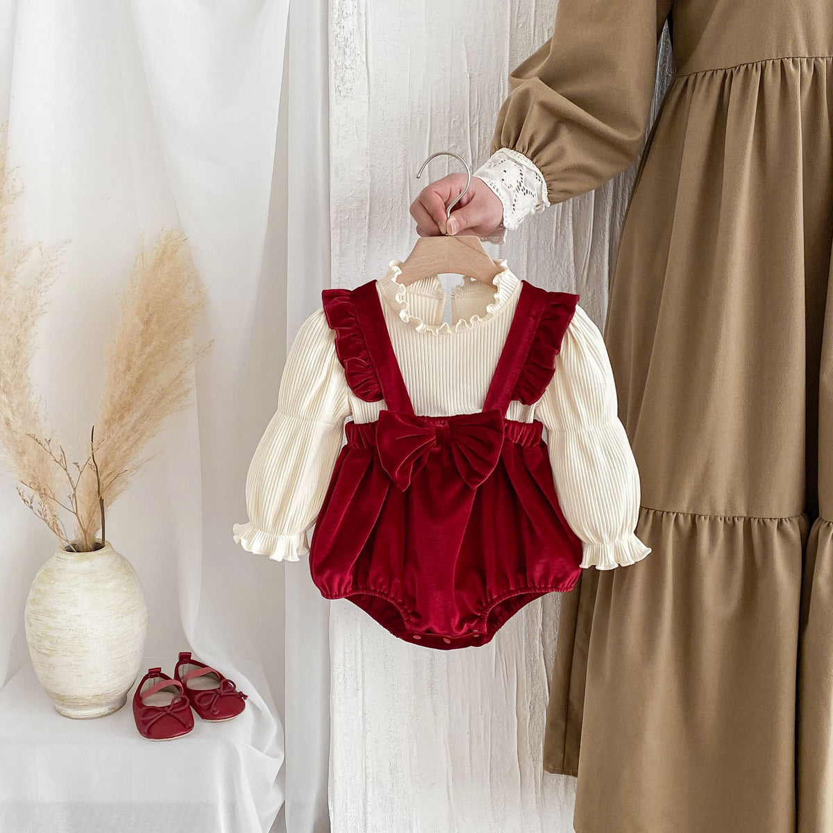 Red velvet suspender romper and cream ruffle blouse on a hanger