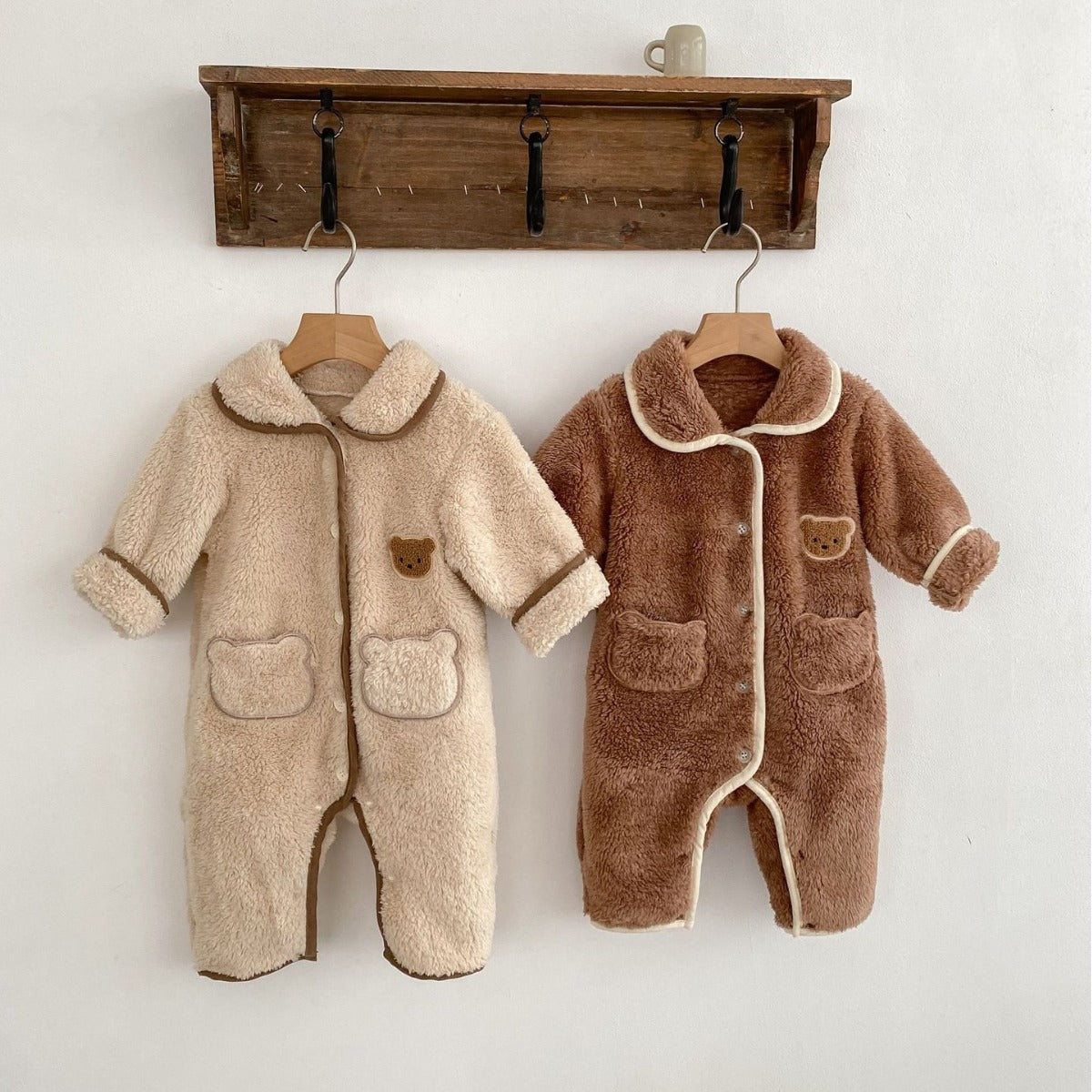 Beige and brown teddy bear jumpsuits on a peg rail