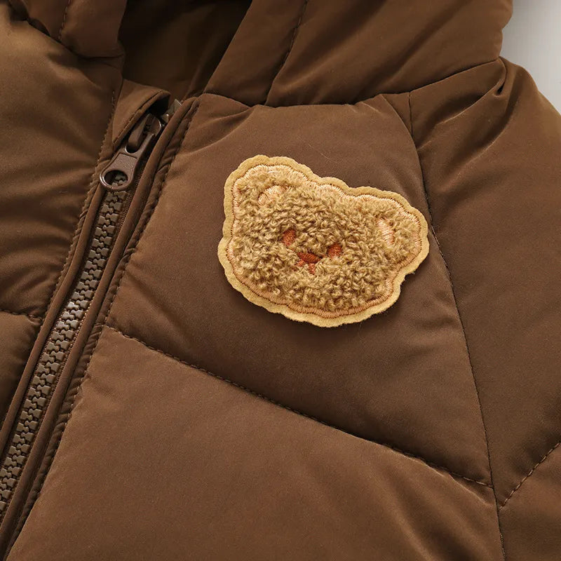 Close-up of teddy bear patch and zip on brown puffer