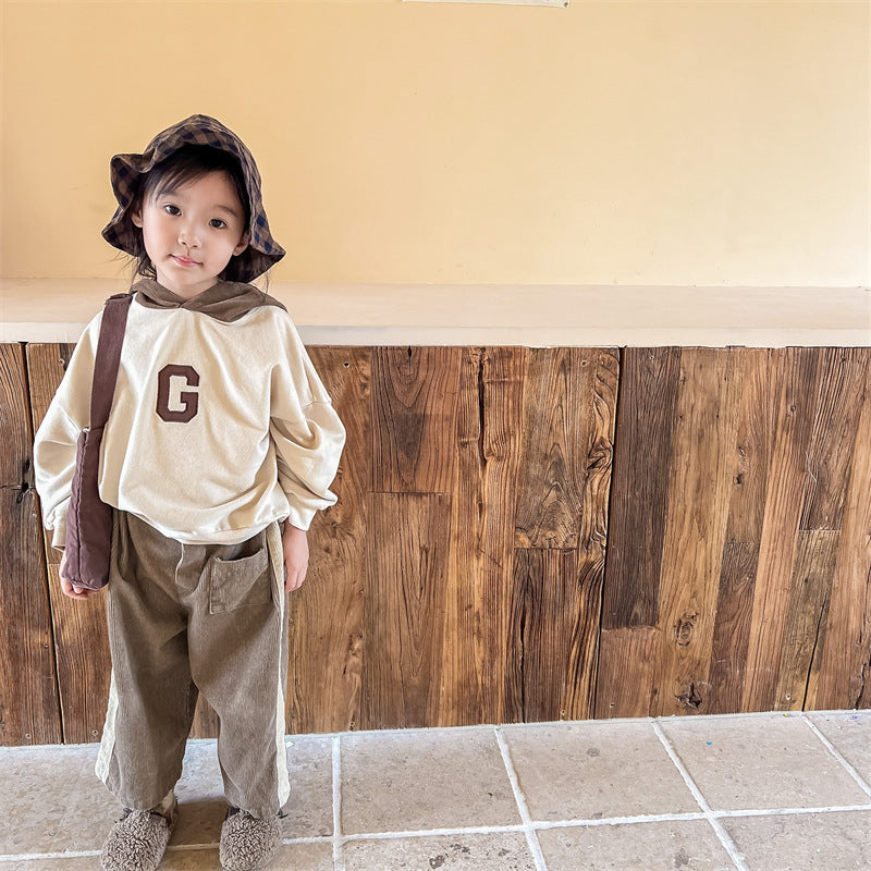 Toddler in corduroy pants with cream sweatshirt and hat