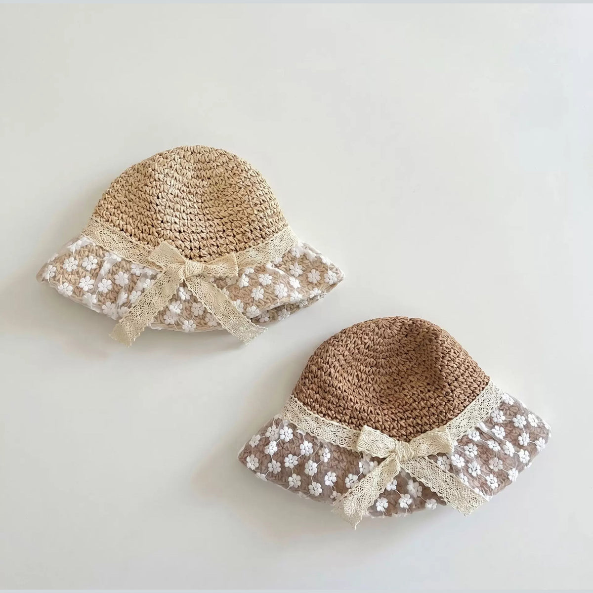 Natural and caramel straw bucket hats with floral lace brims for baby girls