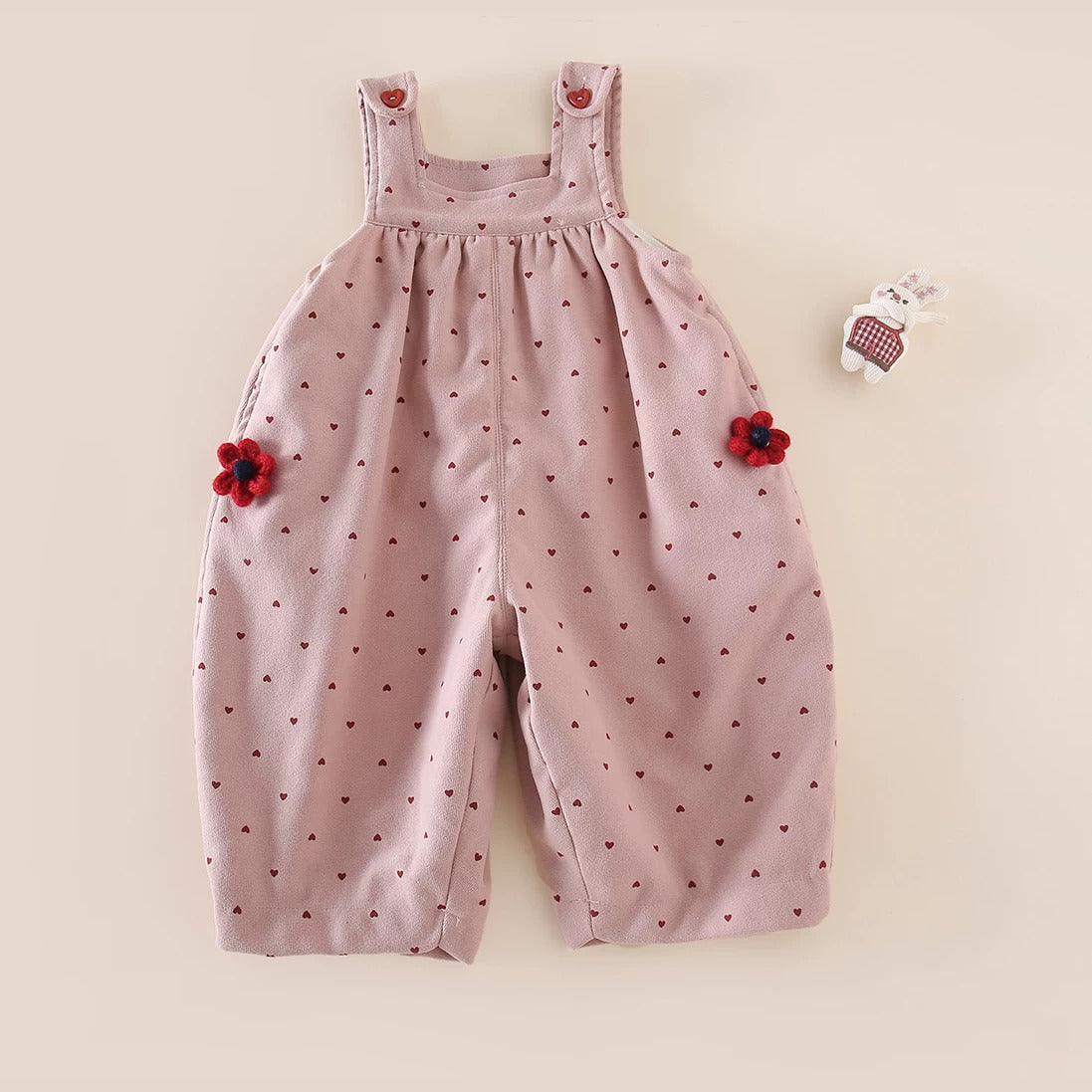 Dusty rose heart-print fleece-lined overalls with red crochet flowers, flat lay