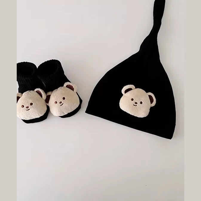 Close-up of a black knot newborn hat and cream bear socks