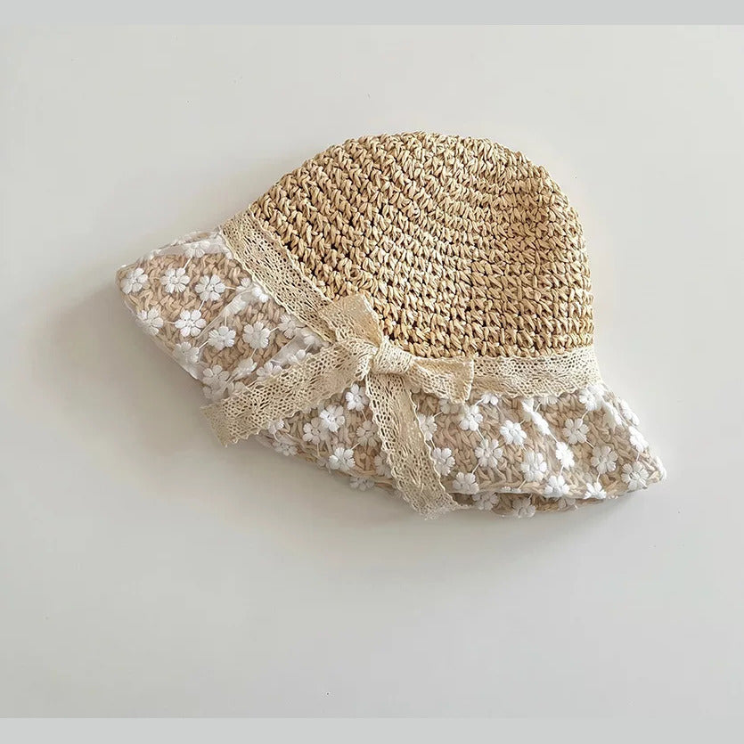 Natural straw baby sun hat with white floral lace brim and lace bow, flat lay