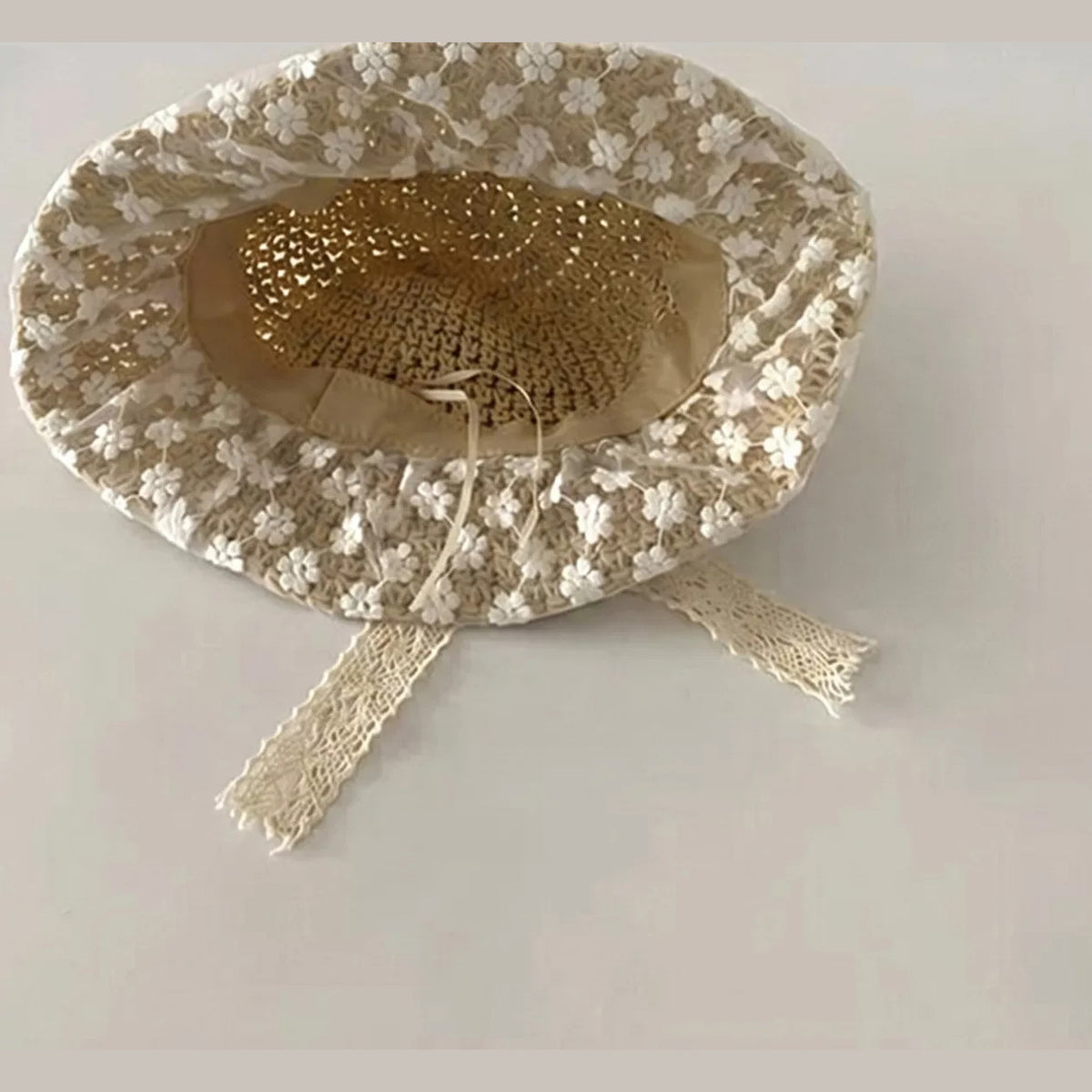 Inside of lace straw baby hat showing lining and lace chin ties