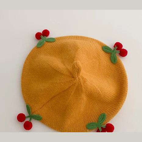 Mustard knit baby beret with crochet cherries, flat lay