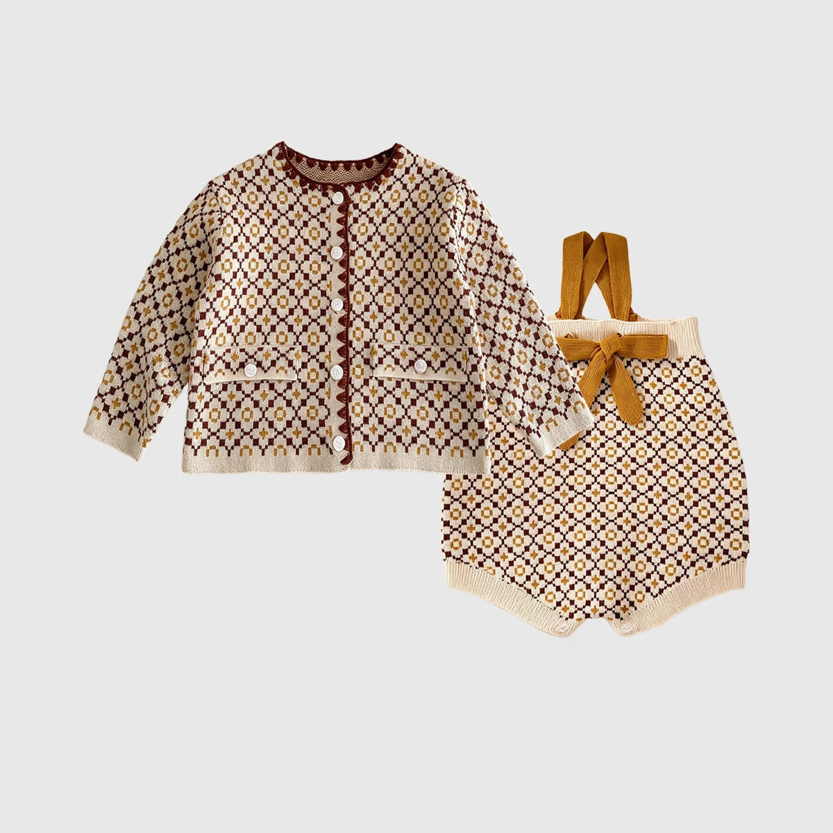Heritage pattern knit cardigan and suspender romper with bow, flat lay