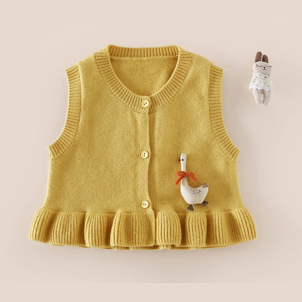 Mustard button-front knit vest with ruffle hem and goose detail, flat lay