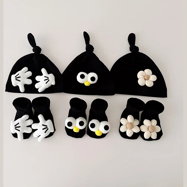 Three black knot baby beanies with matching socks: little hands, googly eyes and daisy