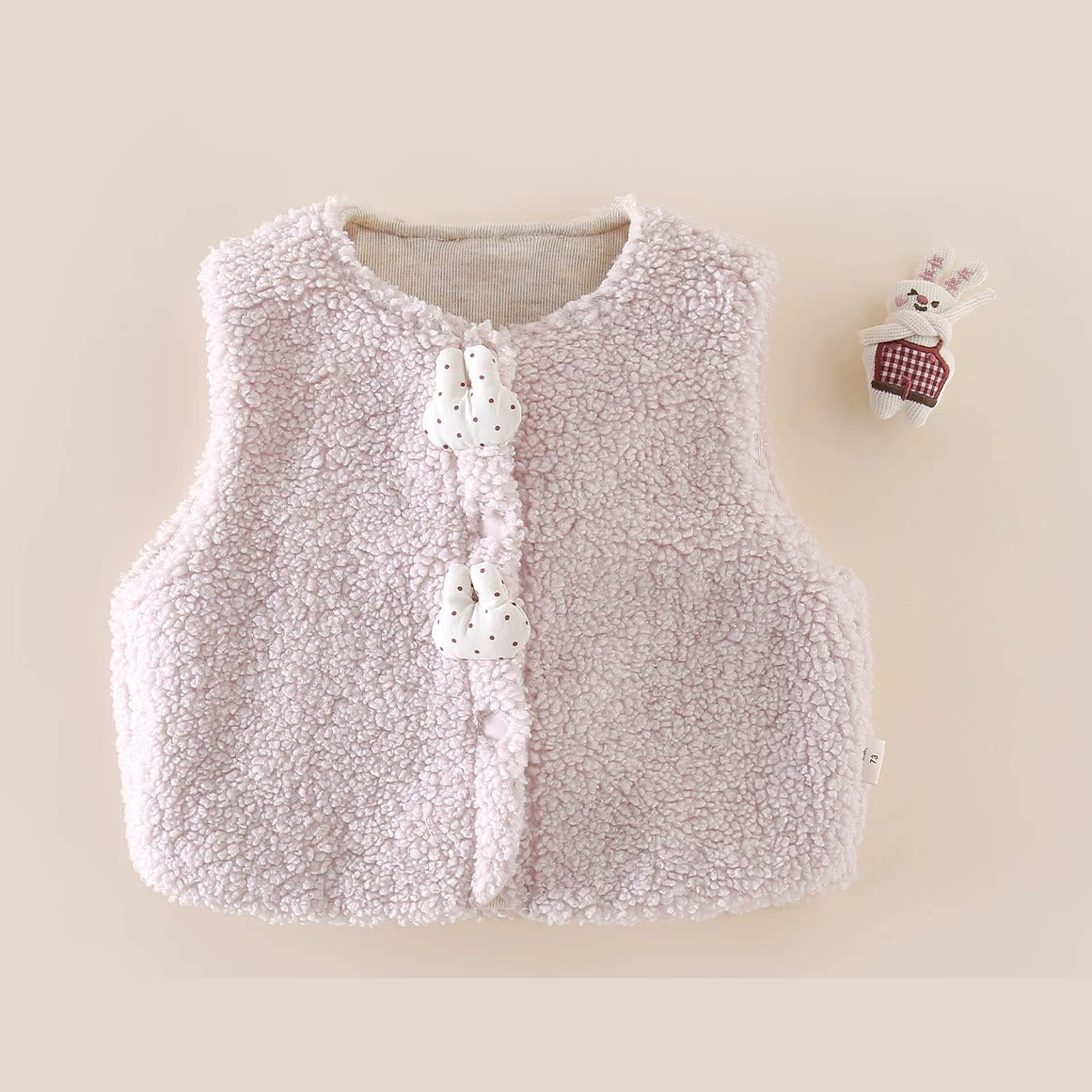 Fluffy blush sherpa vest with bunny toggles, flat lay