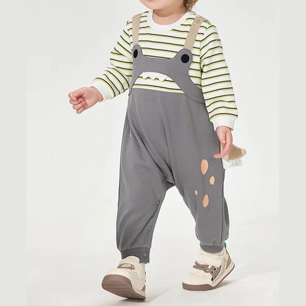 Toddler walking in a grey overall-style romper with striped sleeves