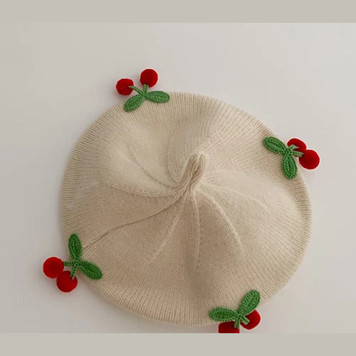 Cream knit baby beret with crochet cherries, flat lay
