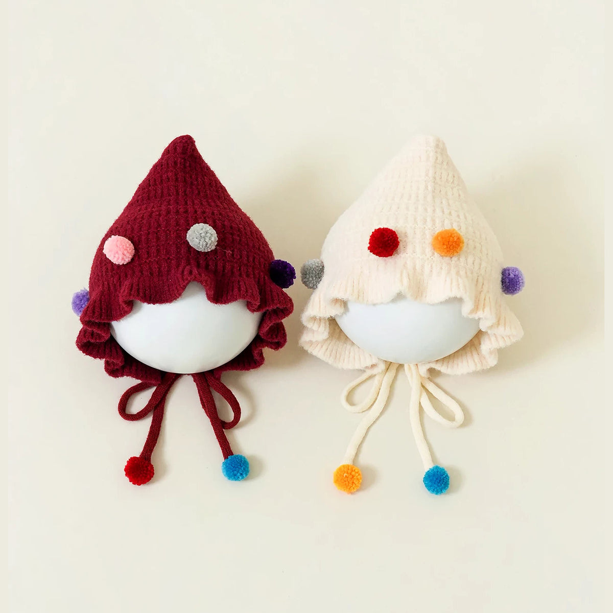 Berry and cream pointed knit baby bonnets with colourful confetti pom-poms