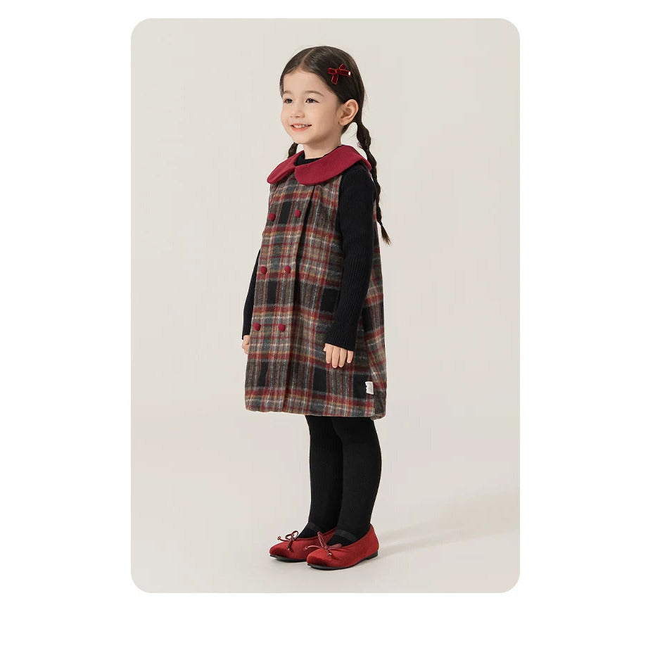Little girl in plaid pinafore dress and black tights, side view