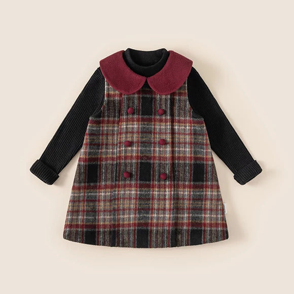 Plaid pinafore layered over black ribbed sweater, flat lay