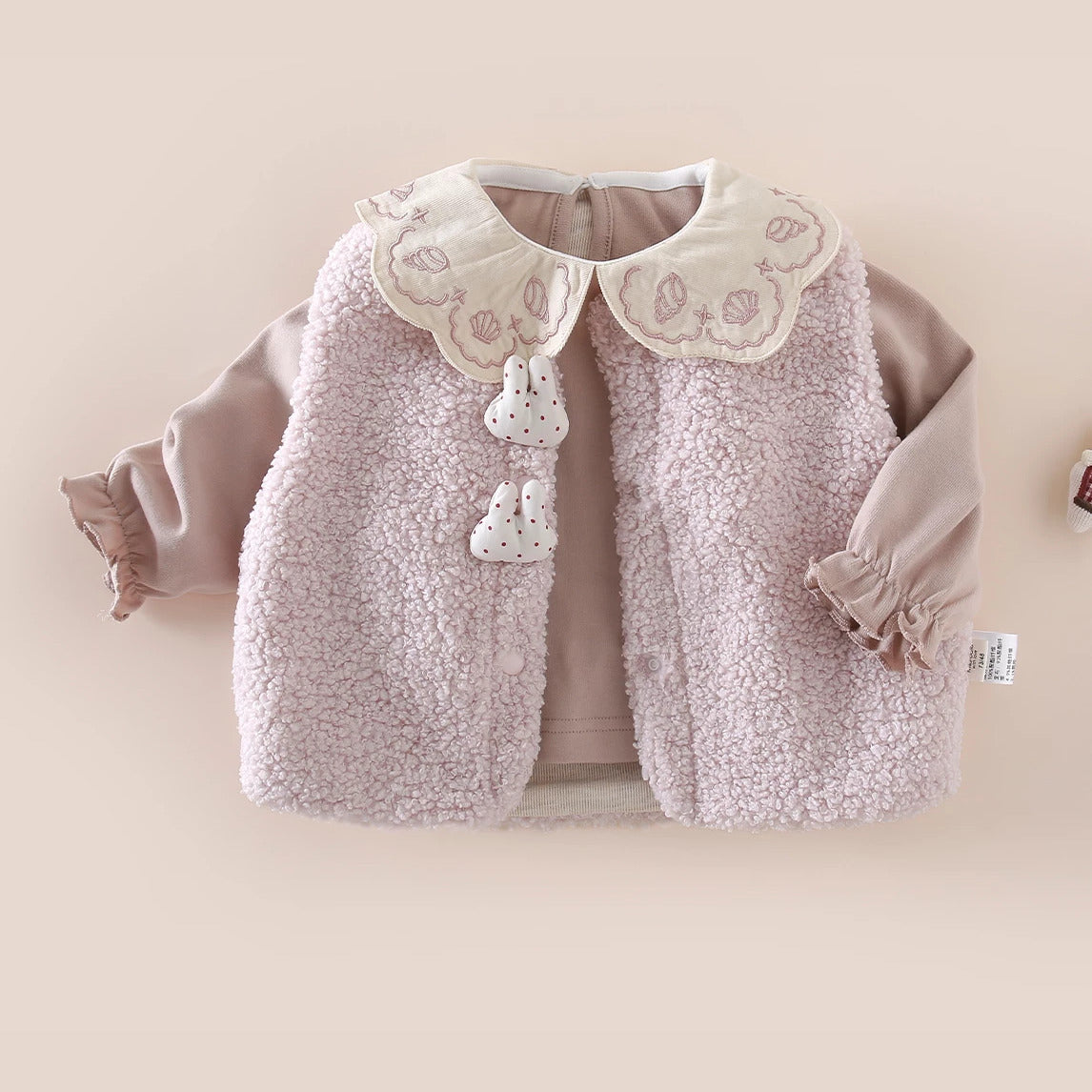 Pink sherpa vest layered over a Peter Pan collar top for baby girls