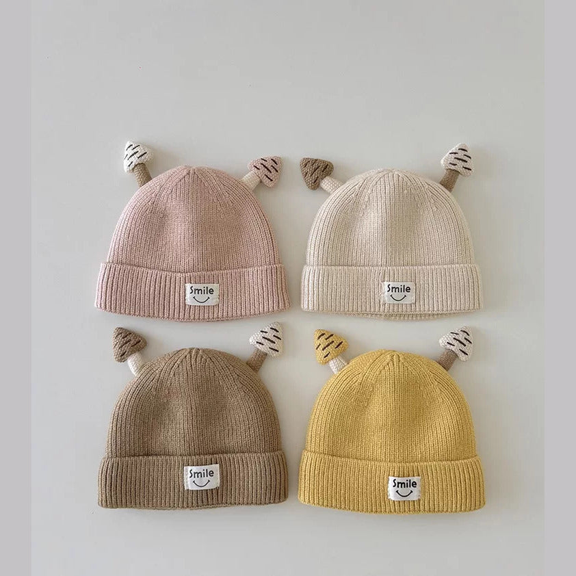 Four ribbed knit baby beanies with mushroom ears in blush, cream, latte and mustard