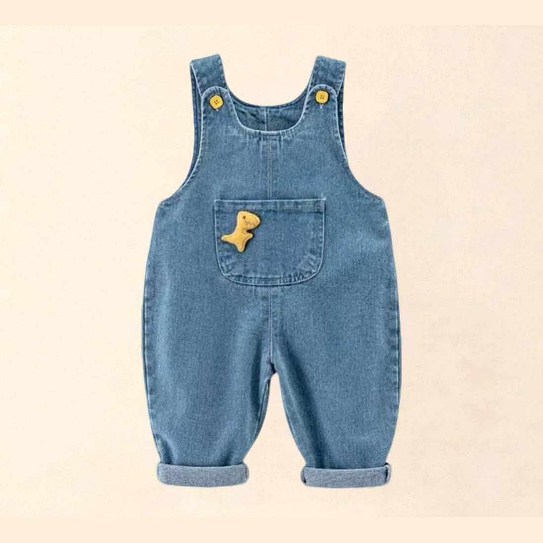 Light-wash denim baby overalls with a yellow plush dinosaur on the bib pocket, front view