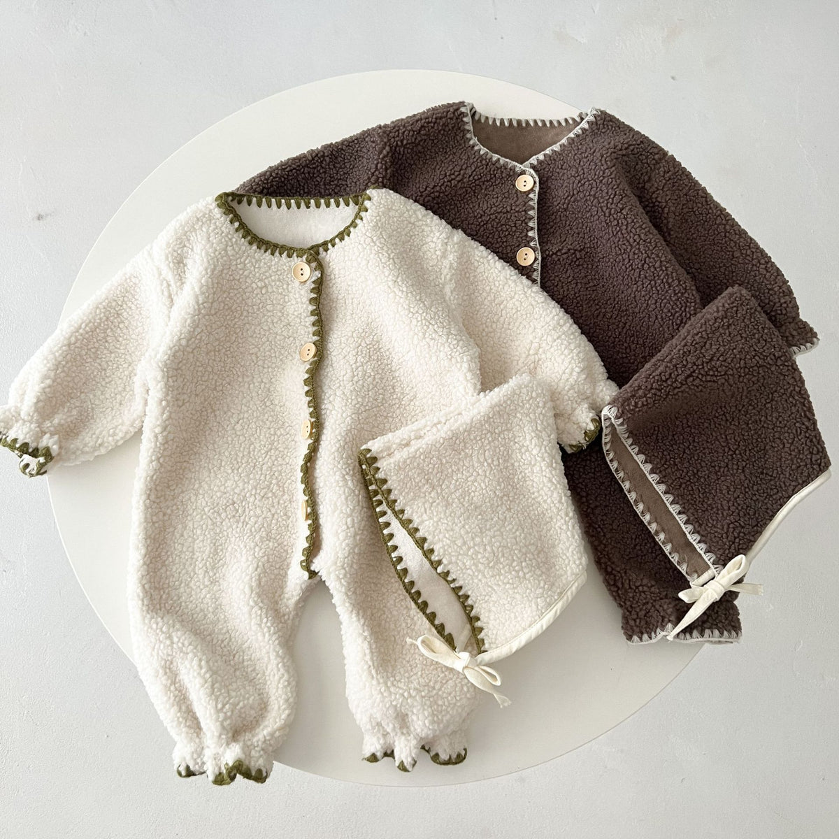 White and brown teddy fleece rompers with bonnets laid flat