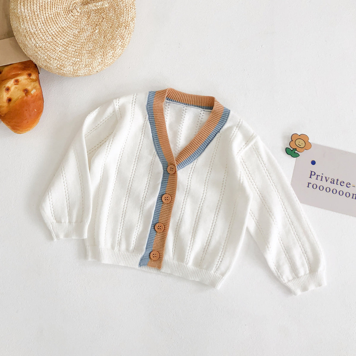 White pointelle knit baby cardigan with orange and blue trim