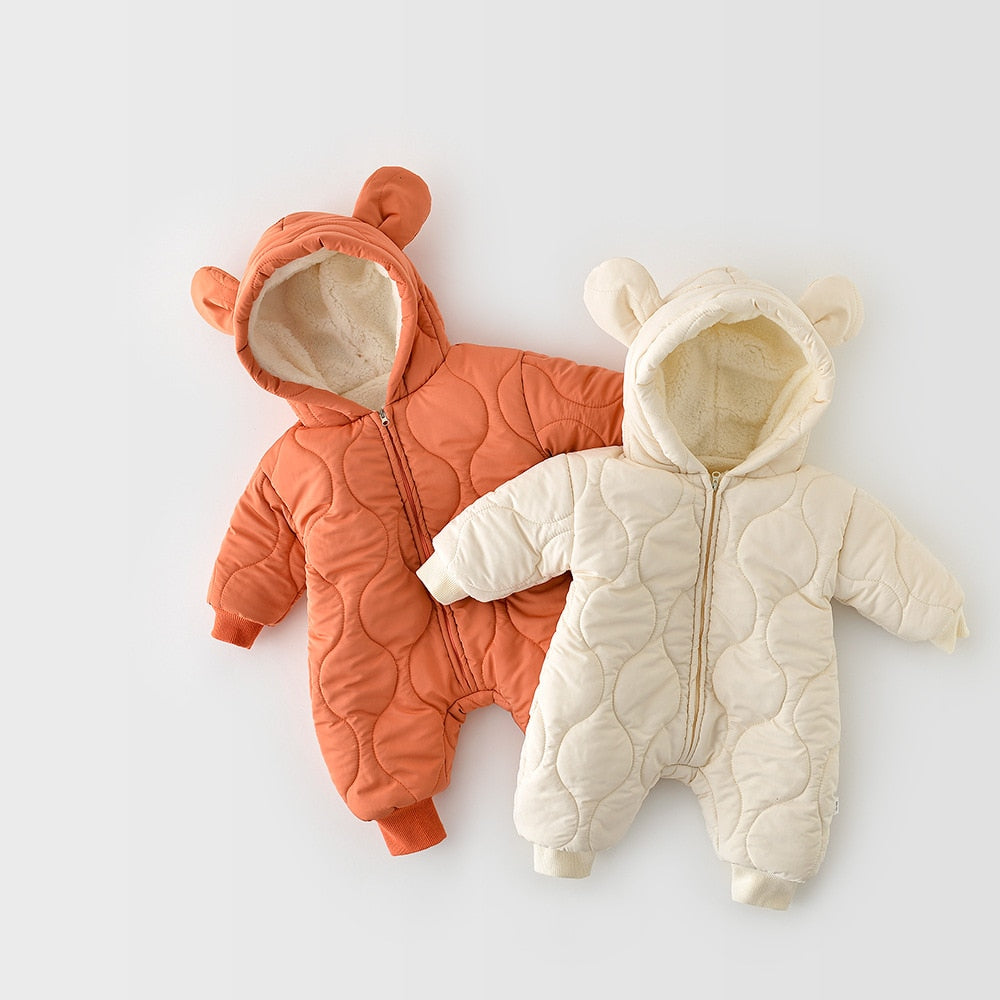 Two quilted baby jumpsuits in cream and burnt orange, each with a hood featuring adorable bear ears. The cozy, fleece-lined interiors and ribbed cuffs make these jumpsuits ideal for cold weather, keeping babies warm and comfortable