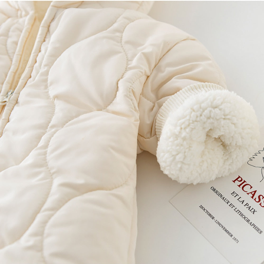 Close-up of a cream-colored quilted baby jumpsuit, showcasing a soft fleece lining inside the cuff. The textured quilted design adds warmth and style, while the plush inner layer ensures extra comfort, making it perfect for keeping babies cozy in colder weather.