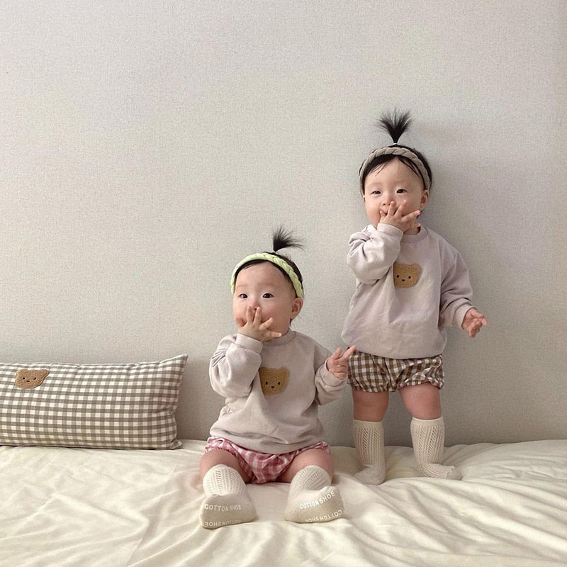 Two babies sitting in bear sweatshirts