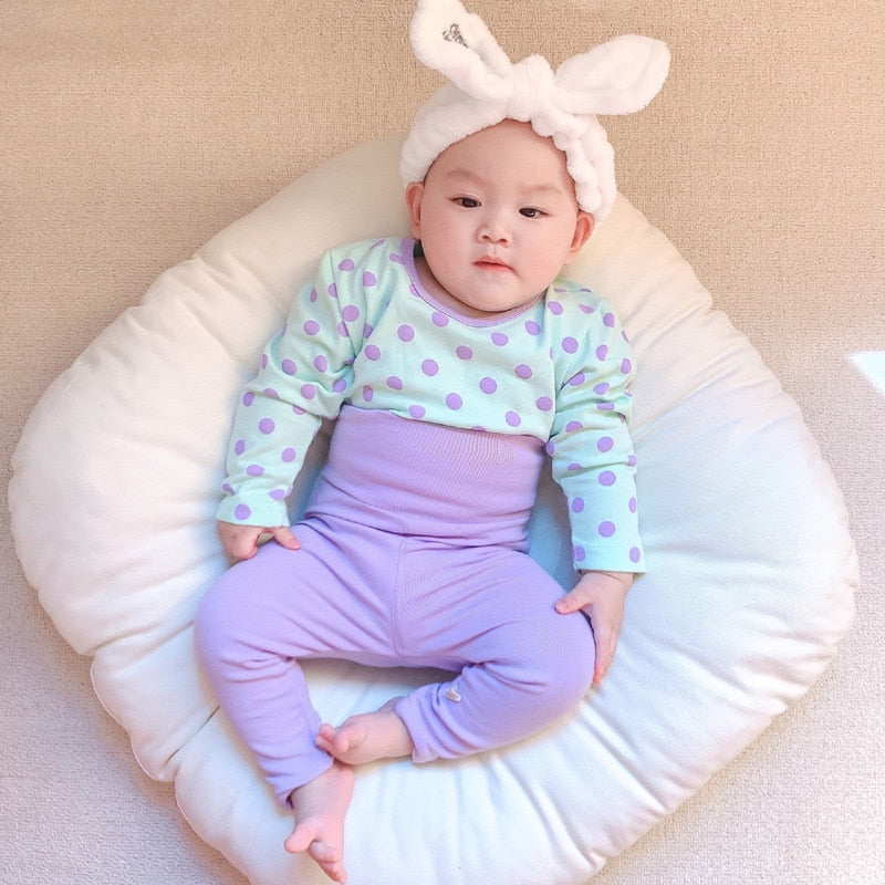 Baby wearing polka dot bodysuit and purple leggings