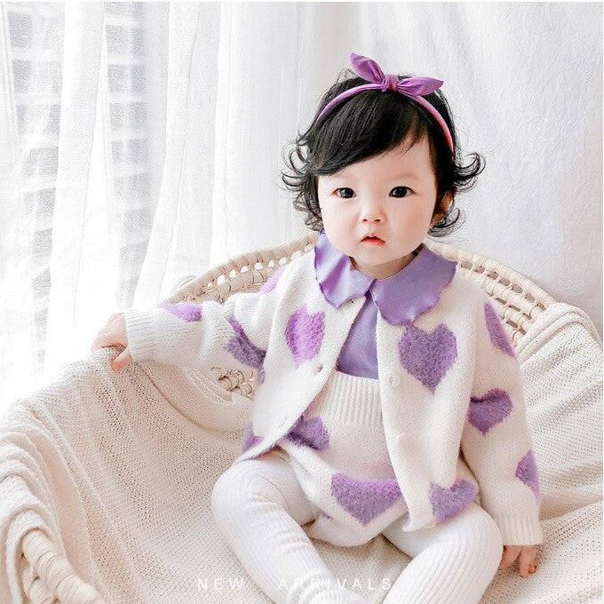 Baby wearing purple heart knit cardigan and romper