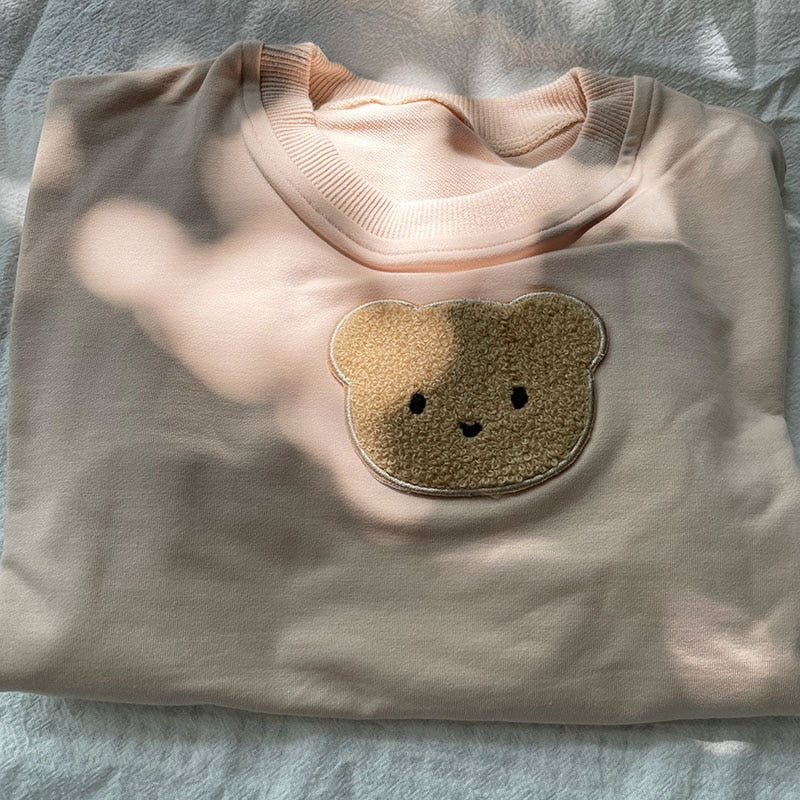 Close-up of teddy bear patch on beige sweatshirt