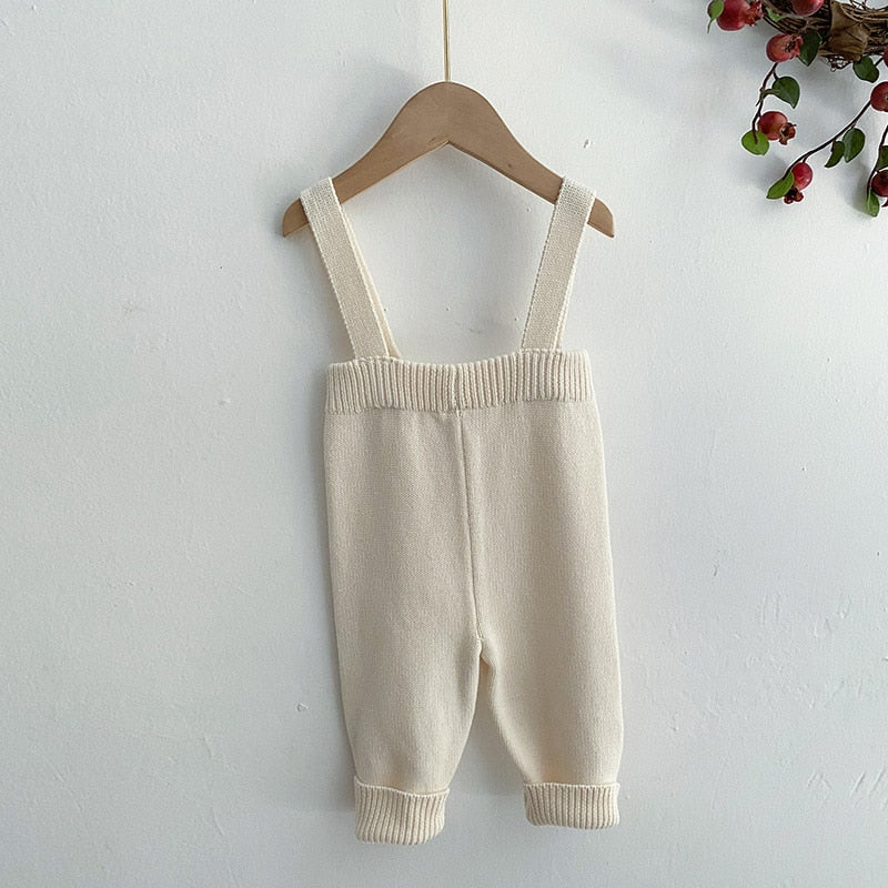 Beige knitted suspender overalls on a hanger