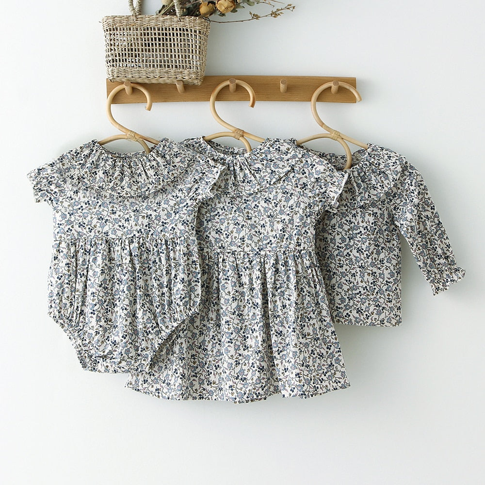 Blue floral romper, dress and shirt hanging on hooks