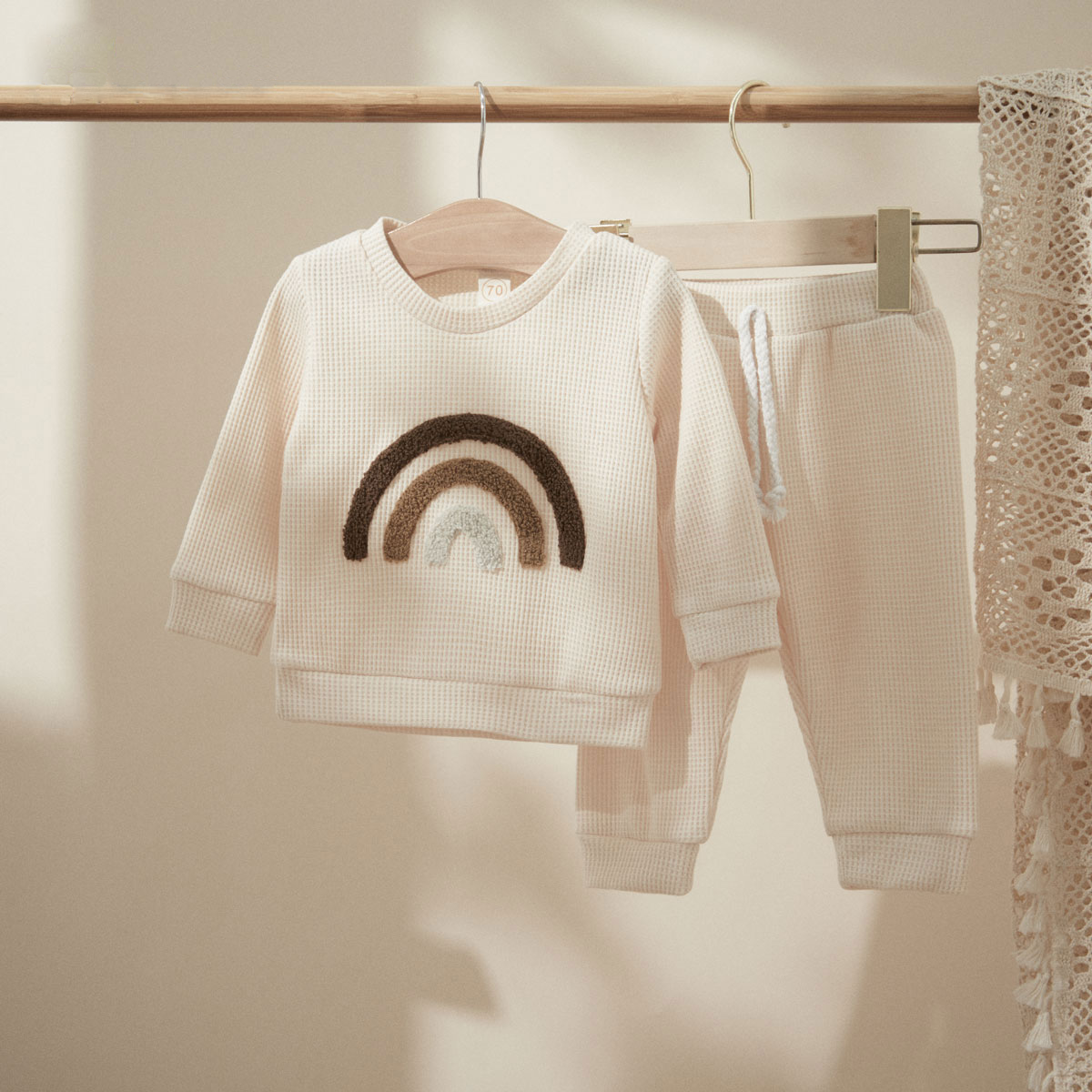 Cream rainbow top and pants on a hanger