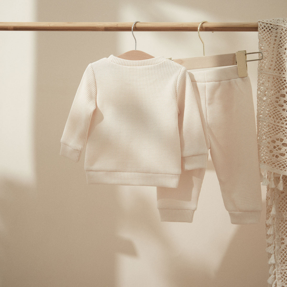 Back of cream ribbed top and pants on a hanger
