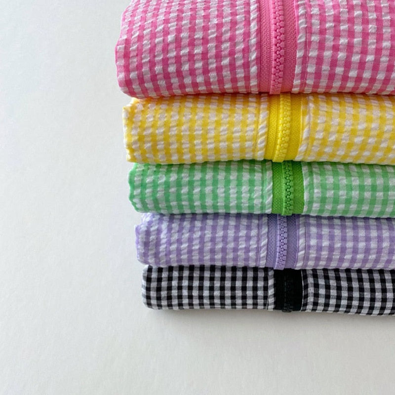 Stack of folded gingham sun jackets in five colours