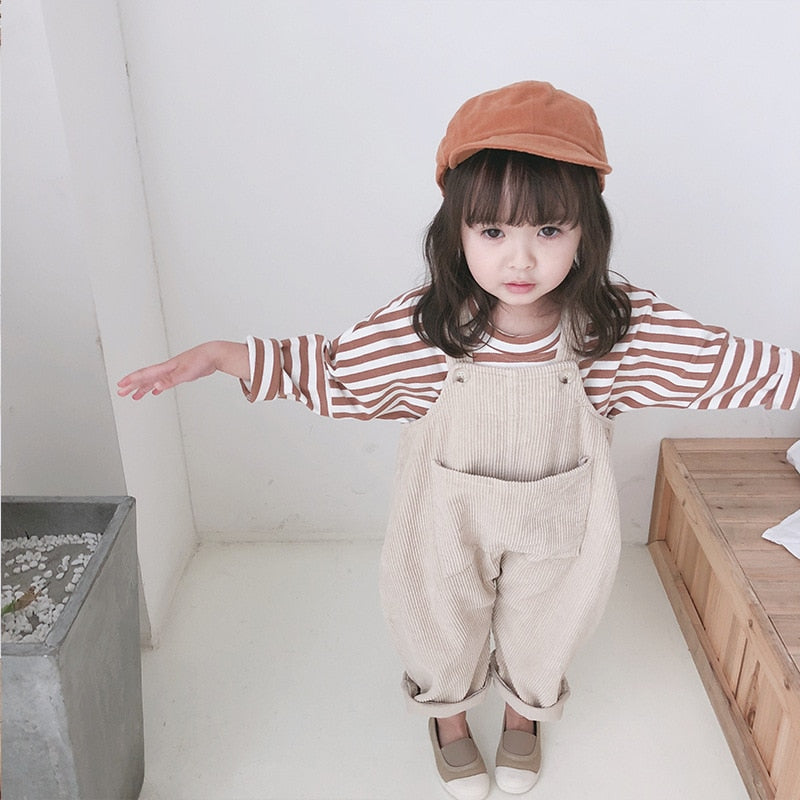 Girl in beige corduroy overalls with arms out