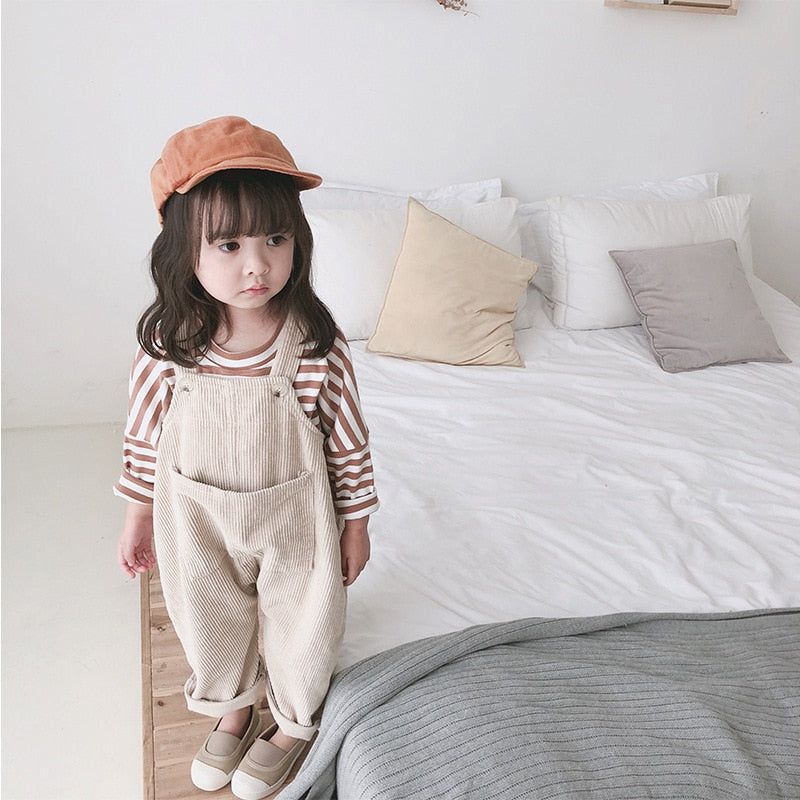 Girl wearing beige corduroy overalls and striped top