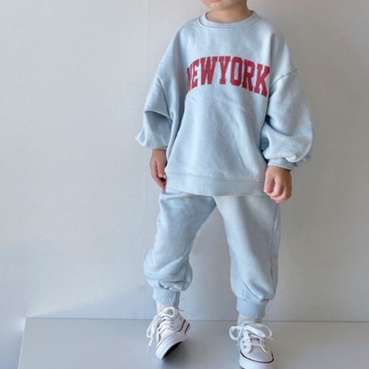 Child wearing light blue NEW YORK tracksuit