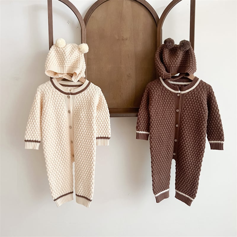 Cream and brown knit rompers with bear hats hanging on a wall rack