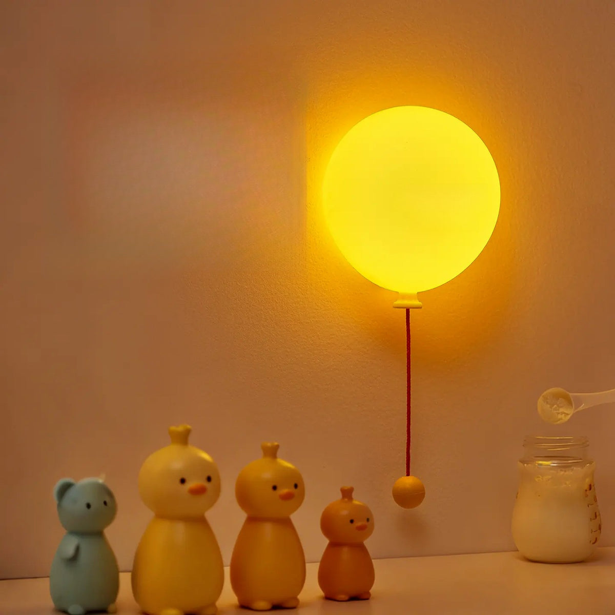 Balloon night light glowing above a shelf of little duck figures