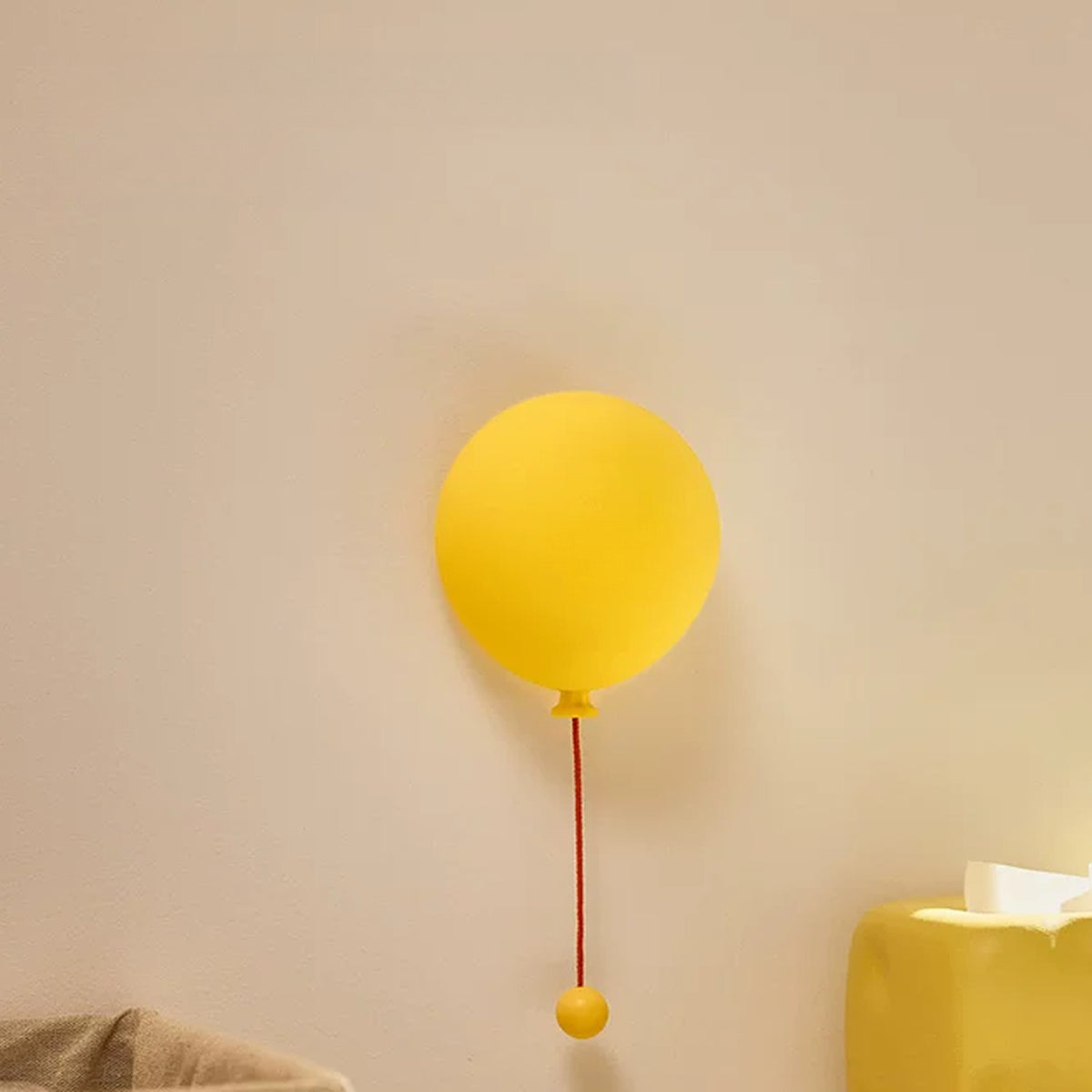 Balloon night light switched off on a cream wall, matte yellow silicone
