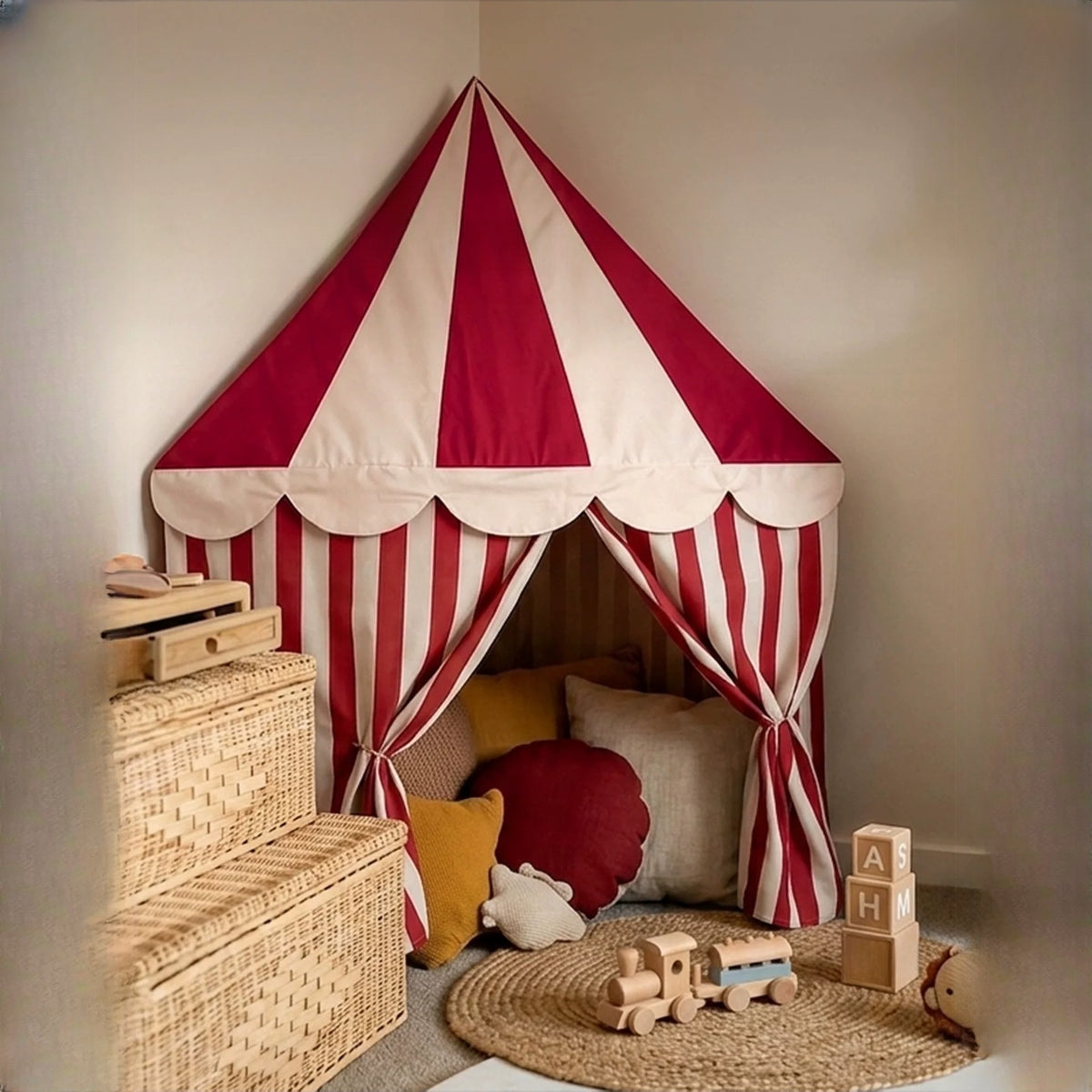 Red and cream striped circus corner tent with cushions in a nursery corner