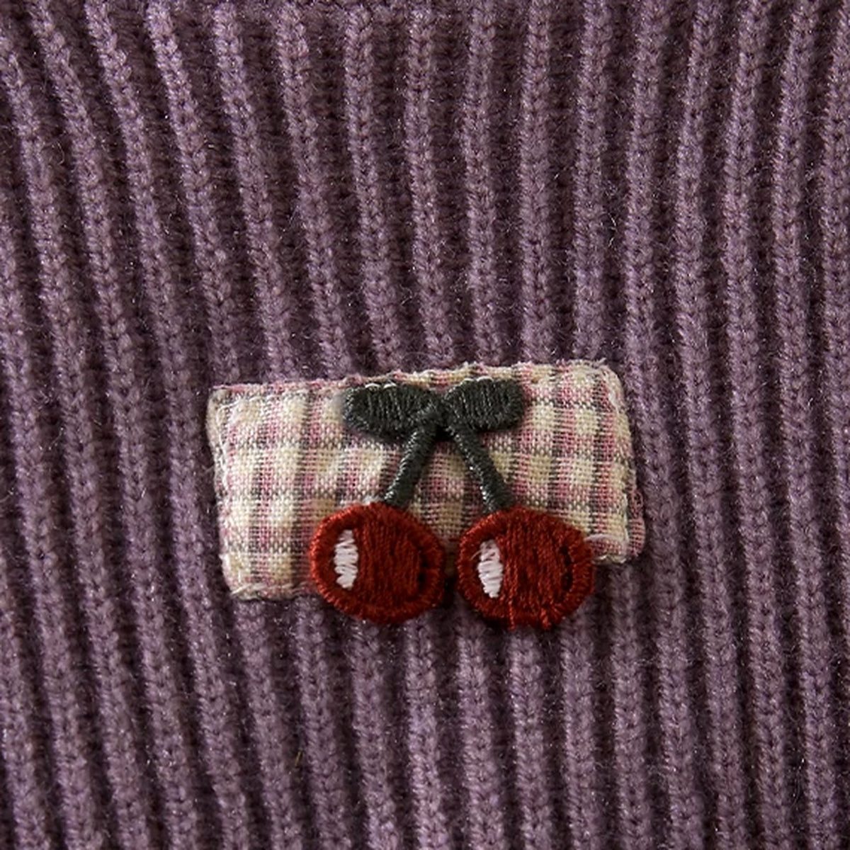 Close-up of the gingham cherry patch on the lilac sweater