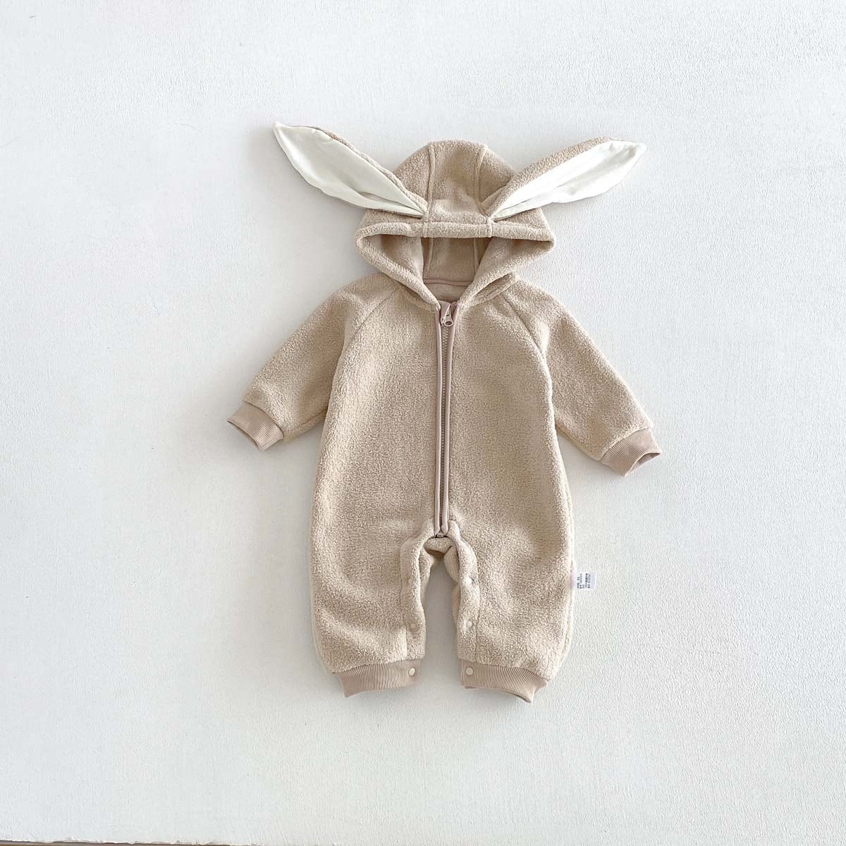 Latte beige hooded baby romper with bunny ears and front zip, flat lay
