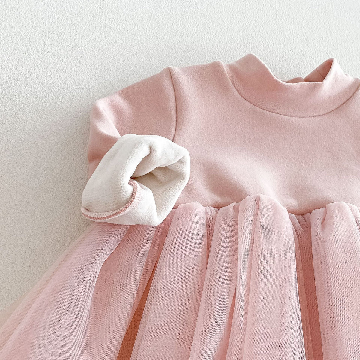 Close-up of the mock neck and soft cuff on the blush dress